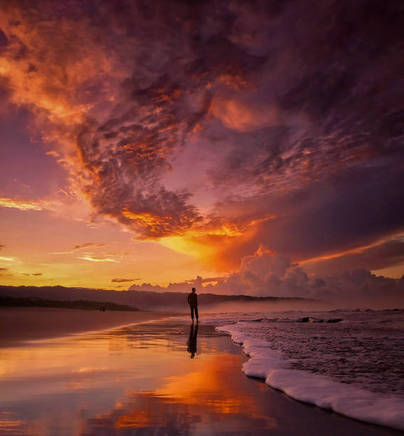 silhouette man standing at beach against sky during sunset